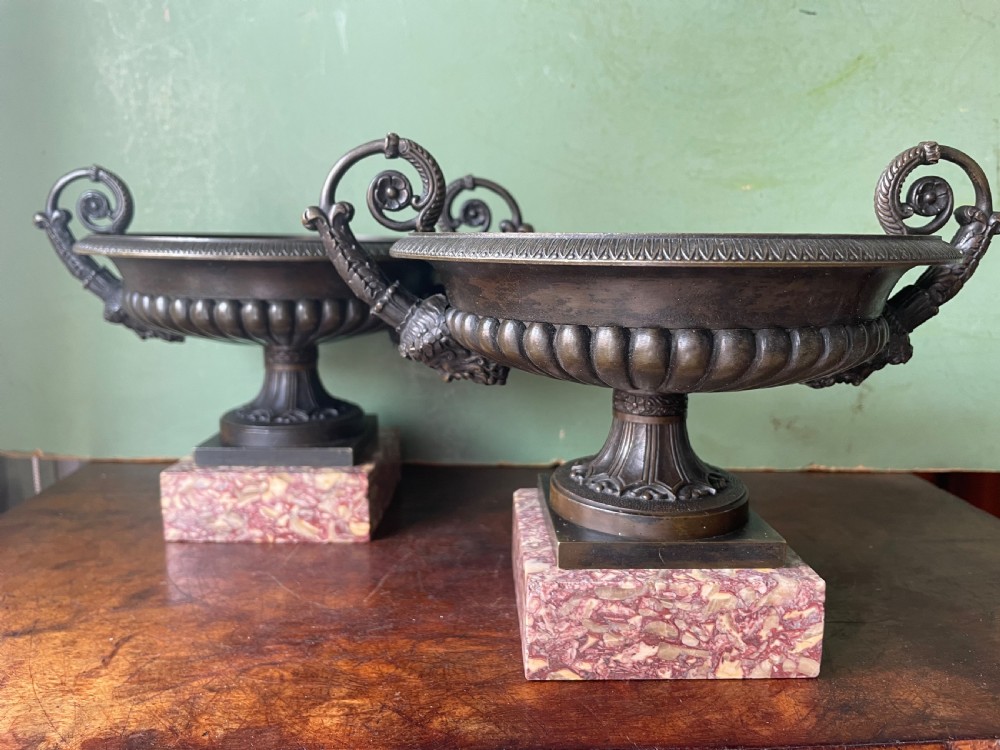 A pair of 19th-century dark bronze tazzas featuring gadrooned bowls and scroll handles, each mounted on a square red mottled marble base. View III