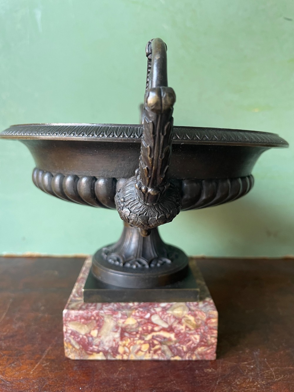 A pair of 19th-century dark bronze tazzas featuring gadrooned bowls and scroll handles, each mounted on a square red mottled marble base. View V