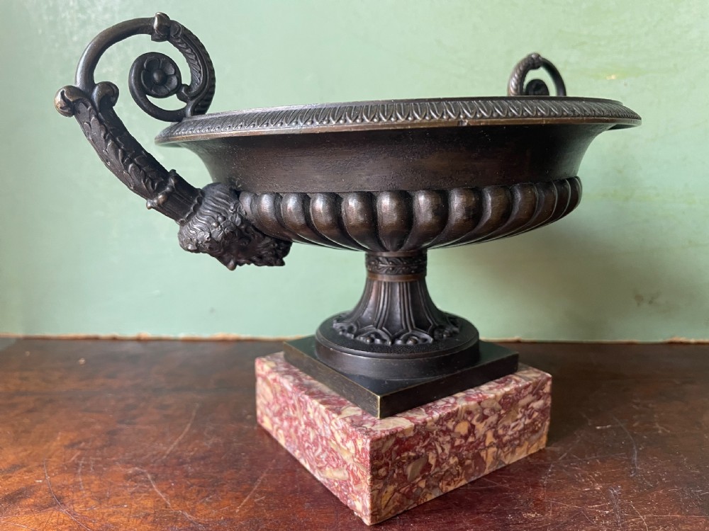 A pair of 19th-century dark bronze tazzas featuring gadrooned bowls and scroll handles, each mounted on a square red mottled marble base. View VIII