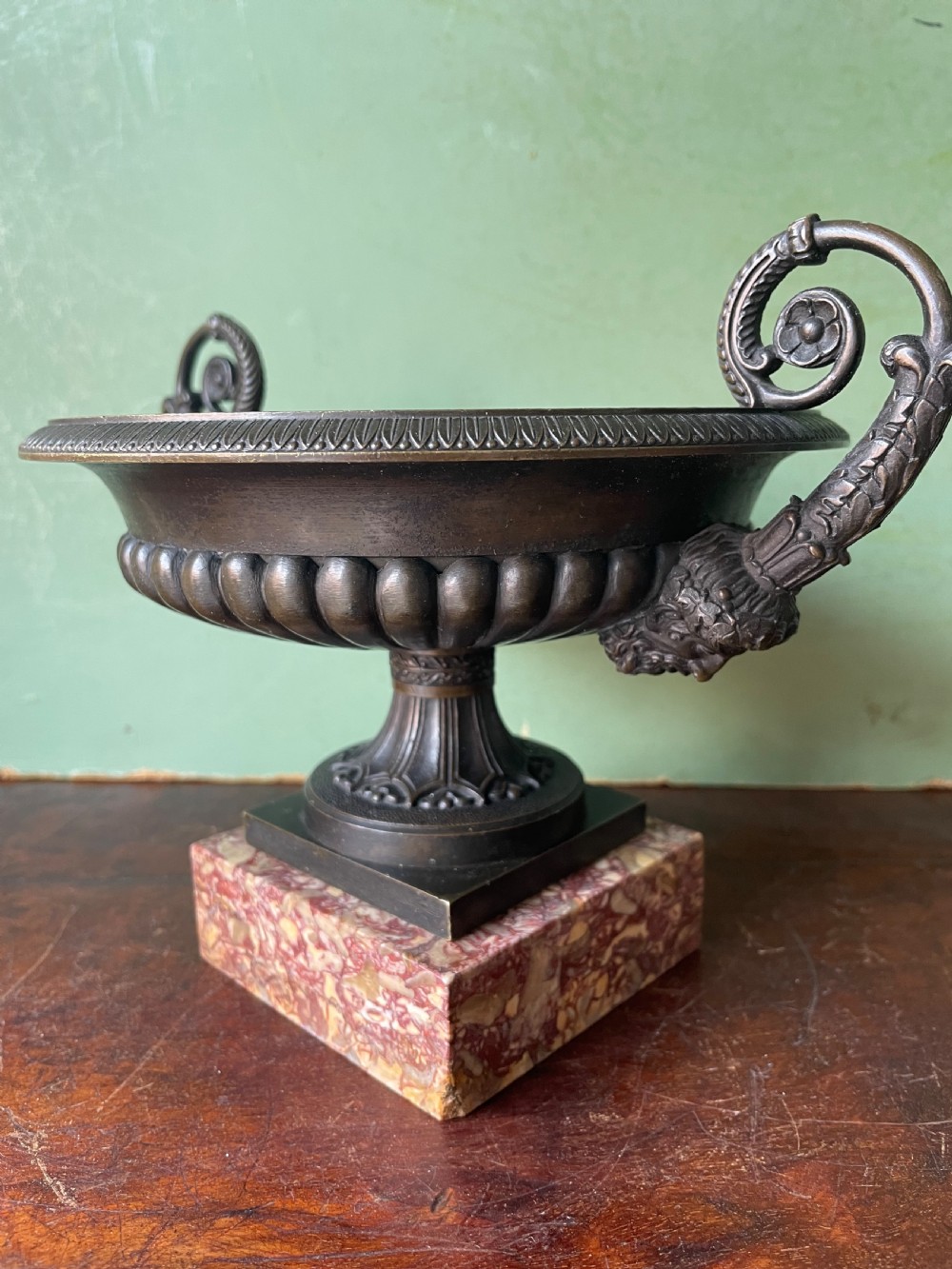 A pair of 19th-century dark bronze tazzas featuring gadrooned bowls and scroll handles, each mounted on a square red mottled marble base. View XIV