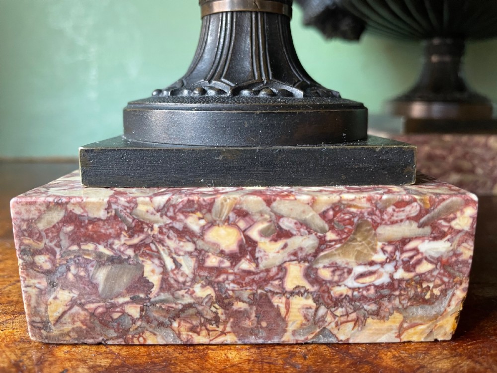 A pair of 19th-century dark bronze tazzas featuring gadrooned bowls and scroll handles, each mounted on a square red mottled marble base. View XVI