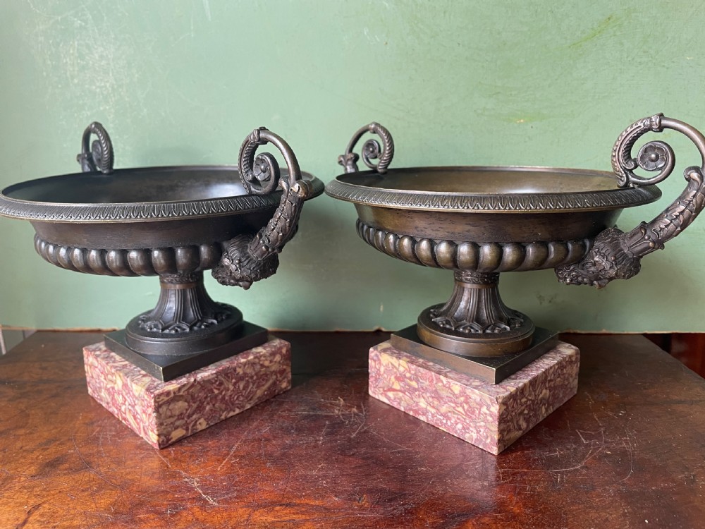 A pair of 19th-century dark bronze tazzas featuring gadrooned bowls and scroll handles, each mounted on a square red mottled marble base. View XIX