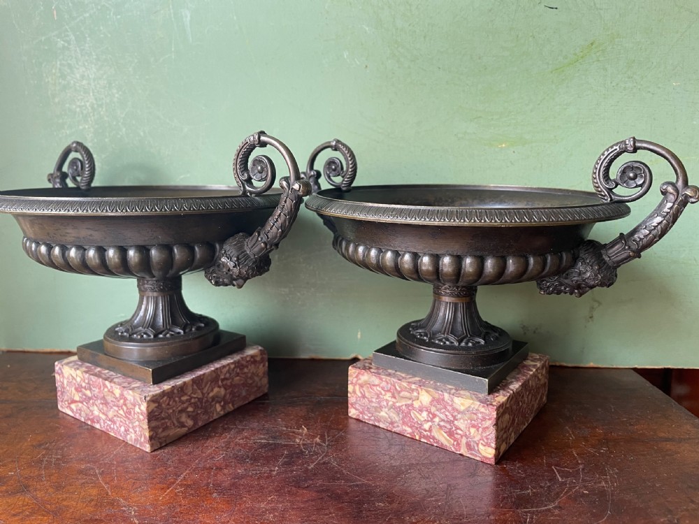 A pair of 19th-century dark bronze tazzas featuring gadrooned bowls and scroll handles, each mounted on a square red mottled marble base. View XX