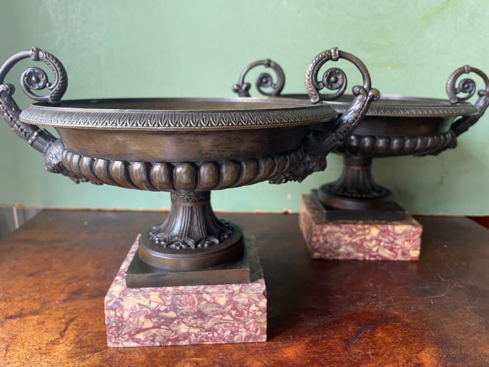 A pair of 19th-century dark bronze tazzas featuring gadrooned bowls and scroll handles, each mounted on a square red mottled marble base. View XXVI