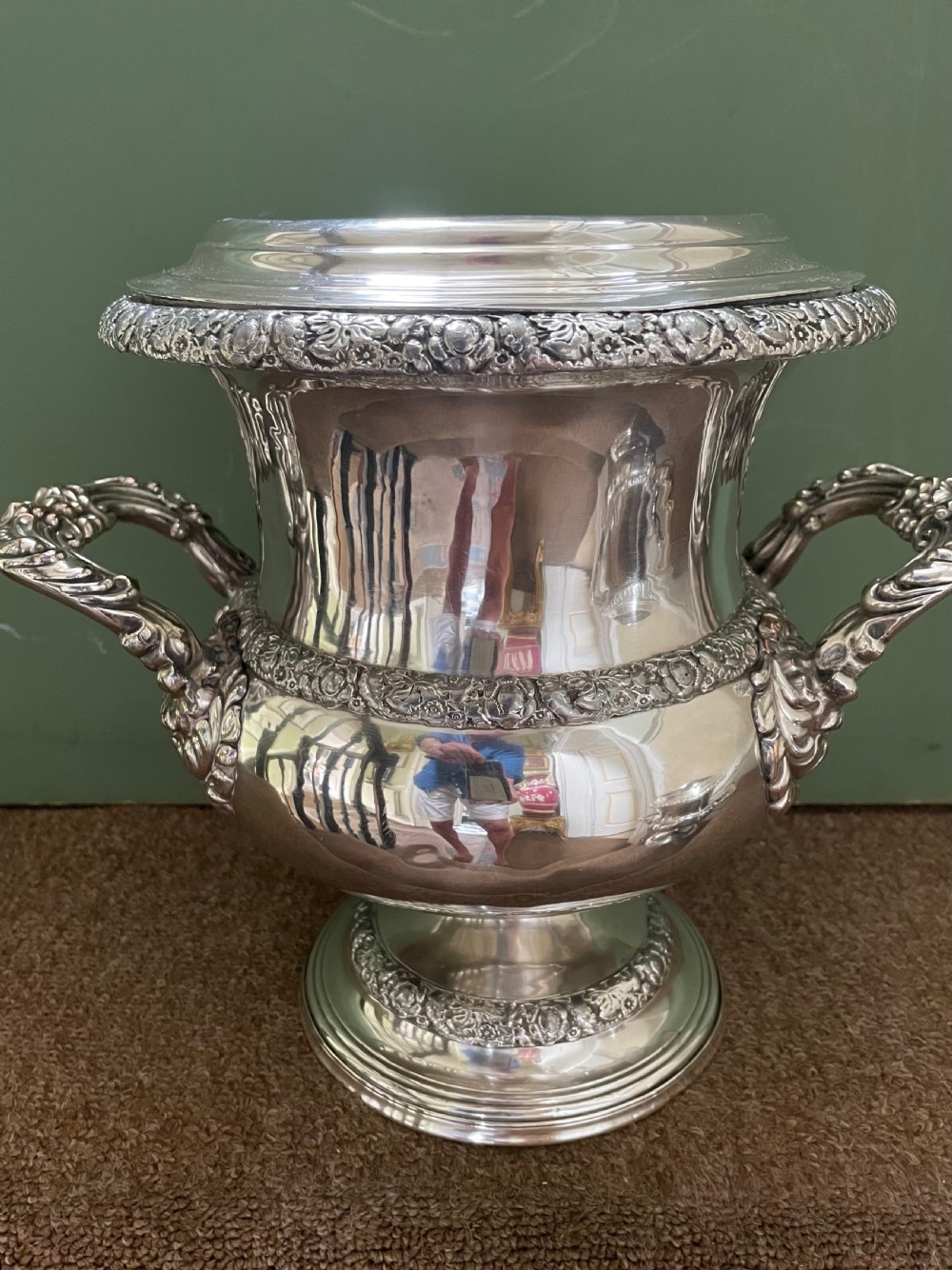 A pair of polished silver-plated campana-form wine coolers featuring ornate foliate handles, intricate relief borders, and pedestal bases. View XI