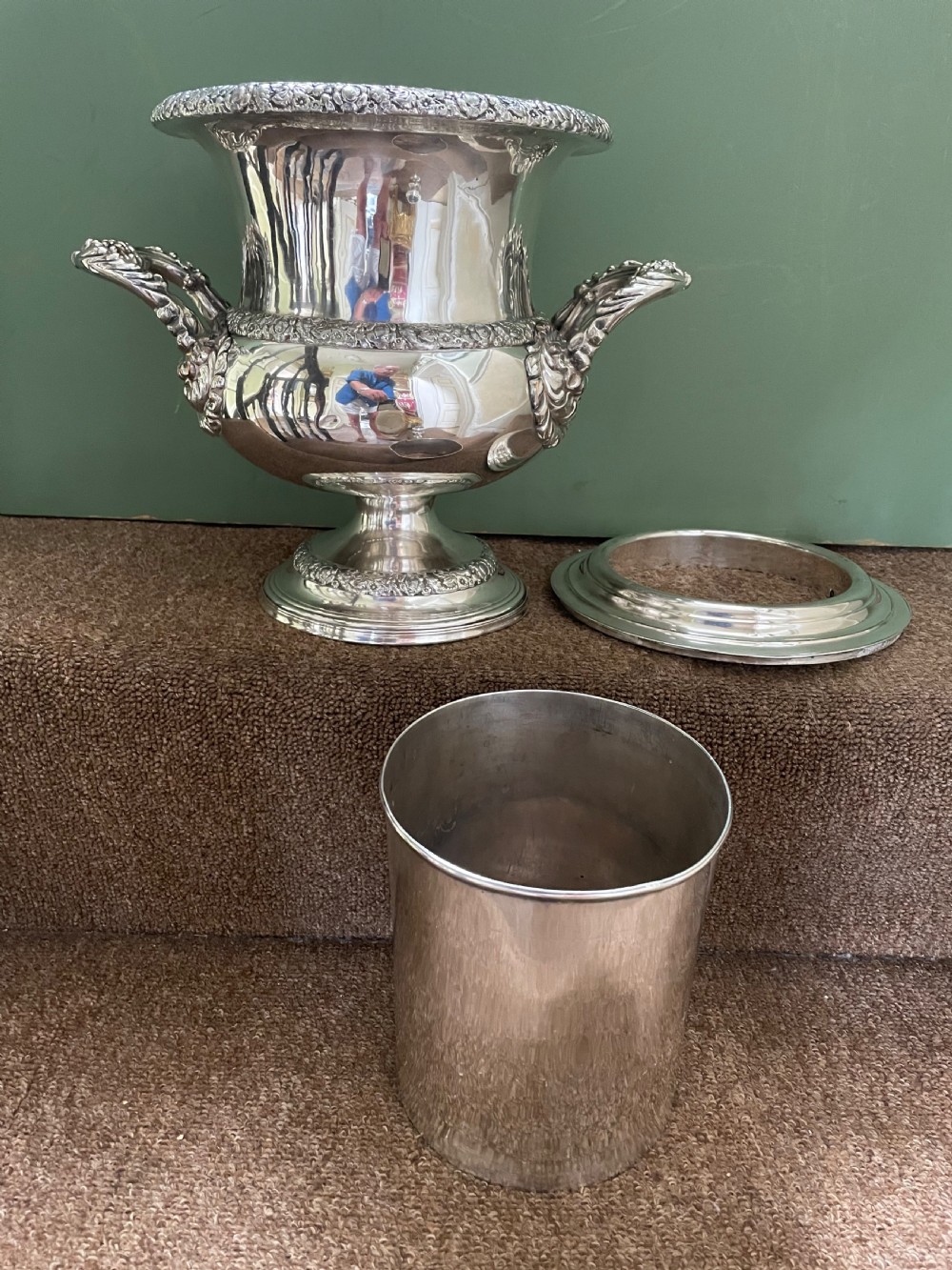 A pair of polished silver-plated campana-form wine coolers featuring ornate foliate handles, intricate relief borders, and pedestal bases. View XII
