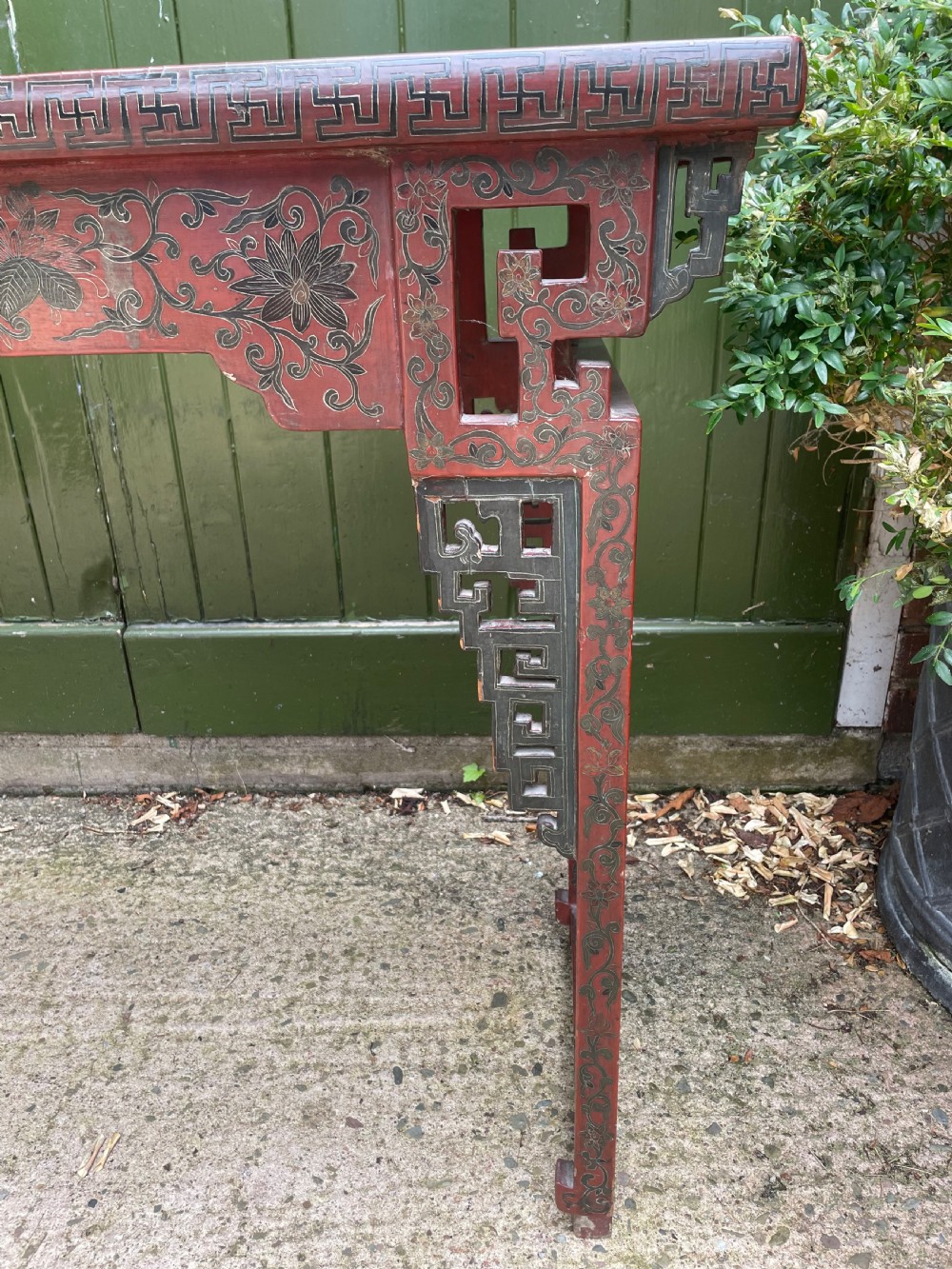 A late nineteenth-century Chinese red lacquered altar table featuring carved decorative spandrels and a patinated surface. View V