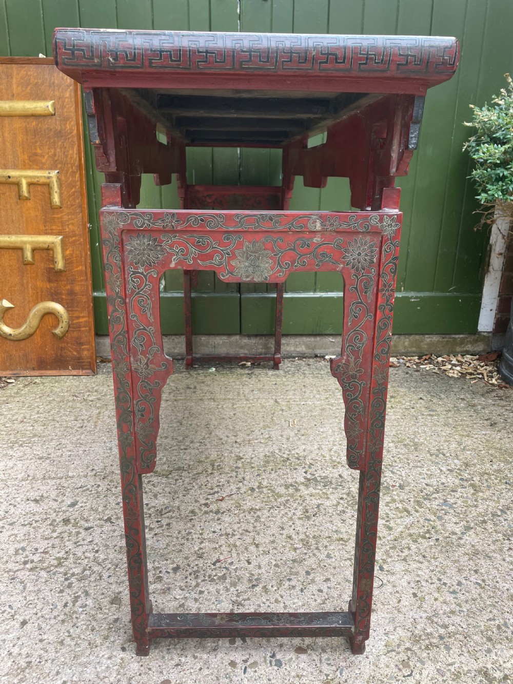 A late nineteenth-century Chinese red lacquered altar table featuring carved decorative spandrels and a patinated surface. View XVI