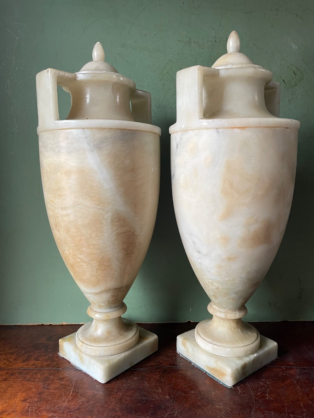 A pair of early nineteenth-century carved cream alabaster classical urns with lids, angular side handles, and square pedestal bases. View III