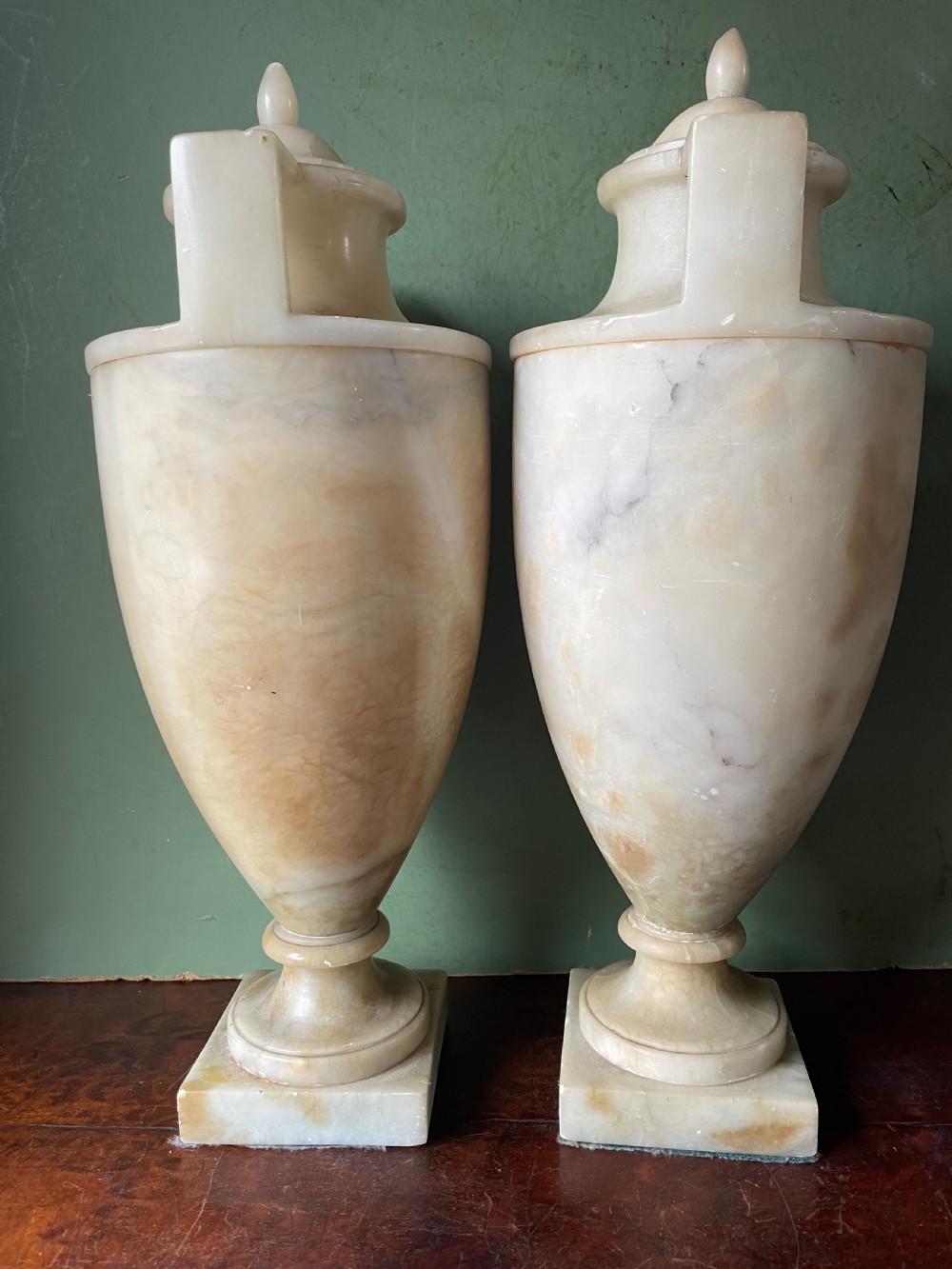 A pair of early nineteenth-century carved cream alabaster classical urns with lids, angular side handles, and square pedestal bases. View IV