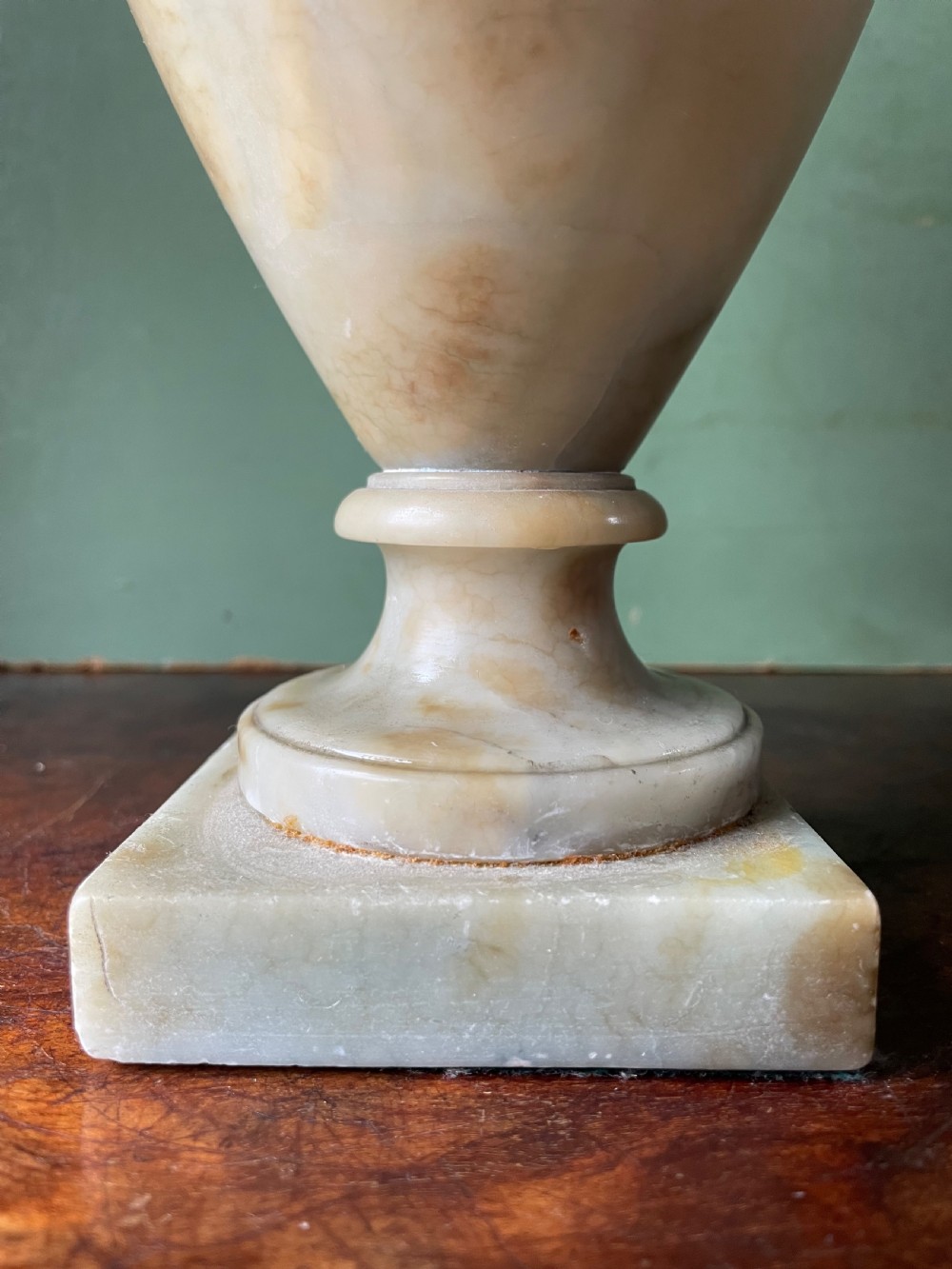 A pair of early nineteenth-century carved cream alabaster classical urns with lids, angular side handles, and square pedestal bases. View IX