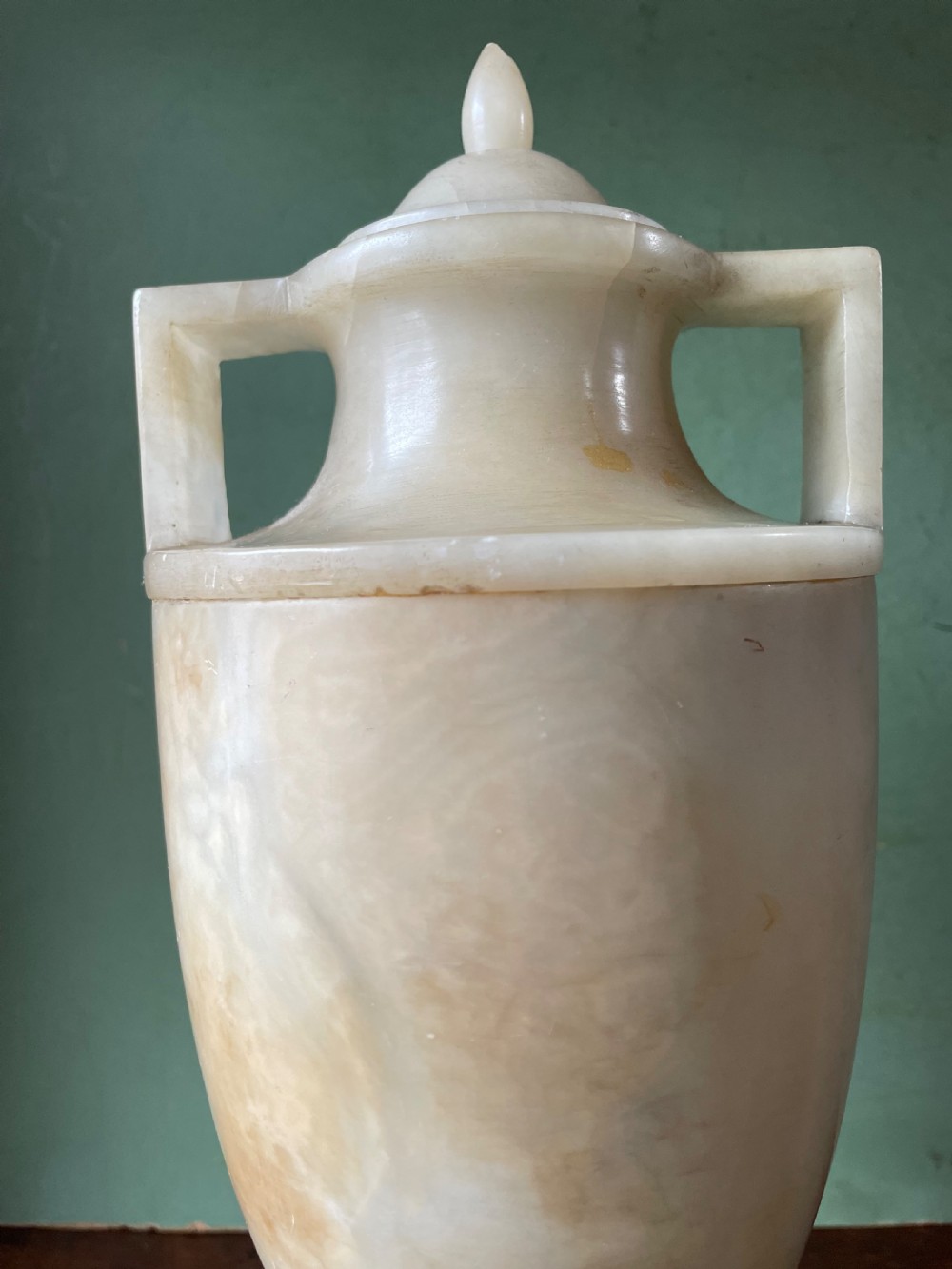 A pair of early nineteenth-century carved cream alabaster classical urns with lids, angular side handles, and square pedestal bases. View XI
