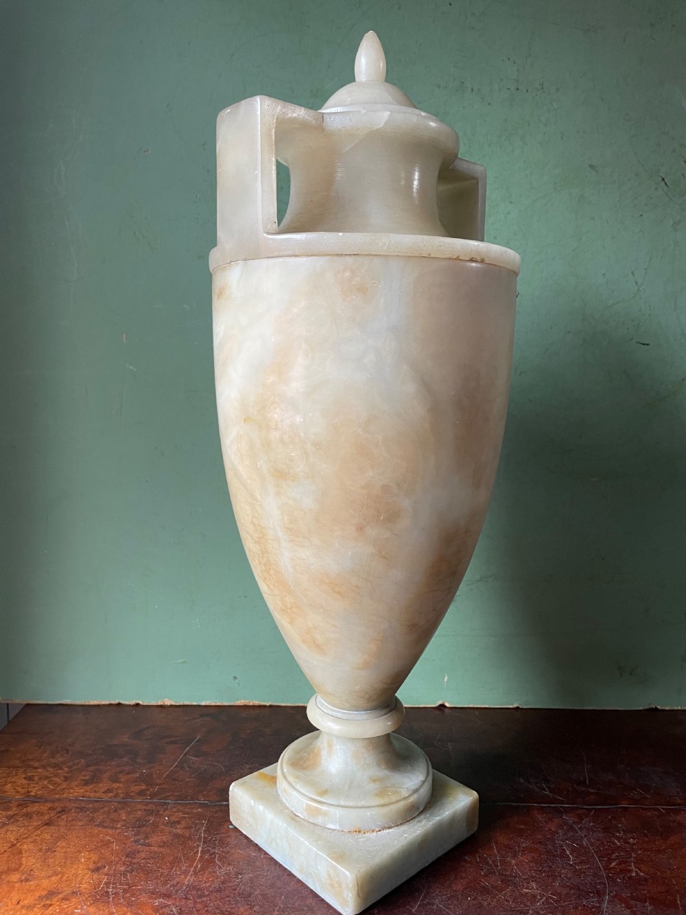 A pair of early nineteenth-century carved cream alabaster classical urns with lids, angular side handles, and square pedestal bases. View XII