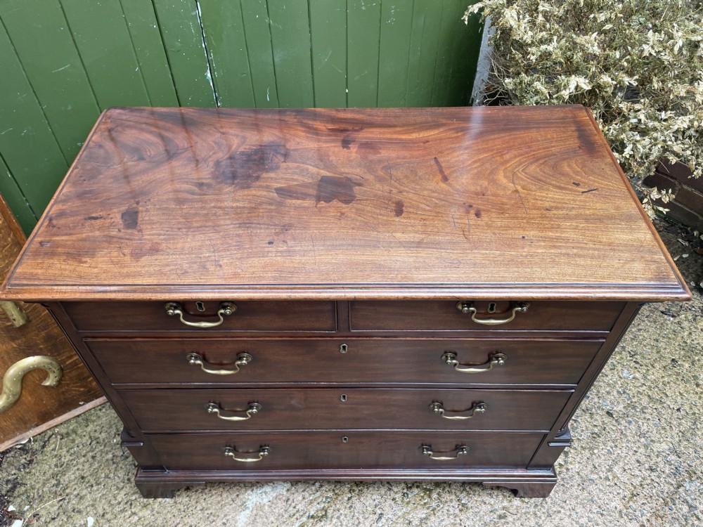 A mid-18th century George III mahogany chest of drawers featuring a two over three drawer layout with brass handles and bracket feet. View XX