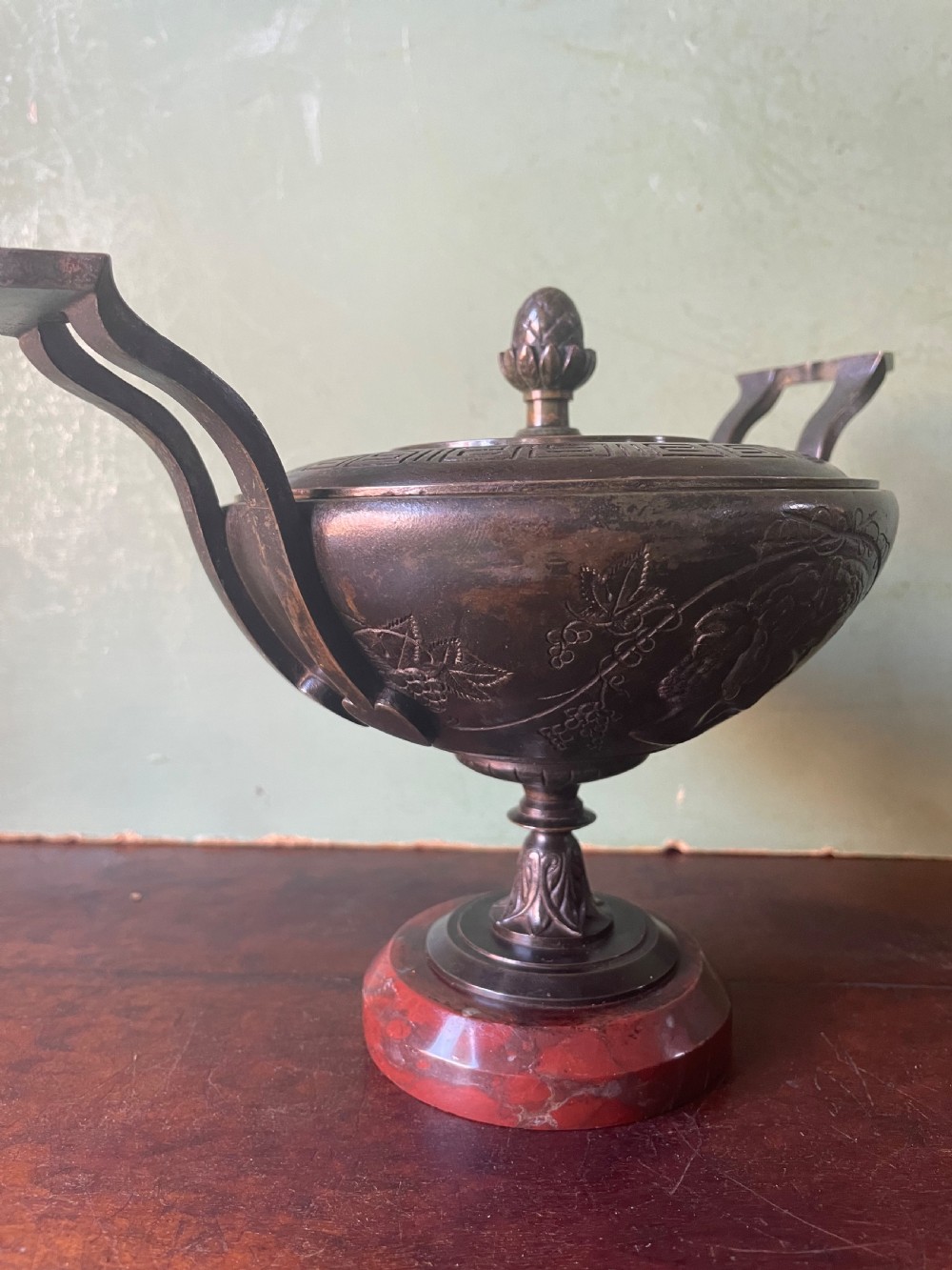 A nineteenth-century bronze lidded tazza featuring Greek key chasing and elevated handles, supported by a round red marble base. View VI