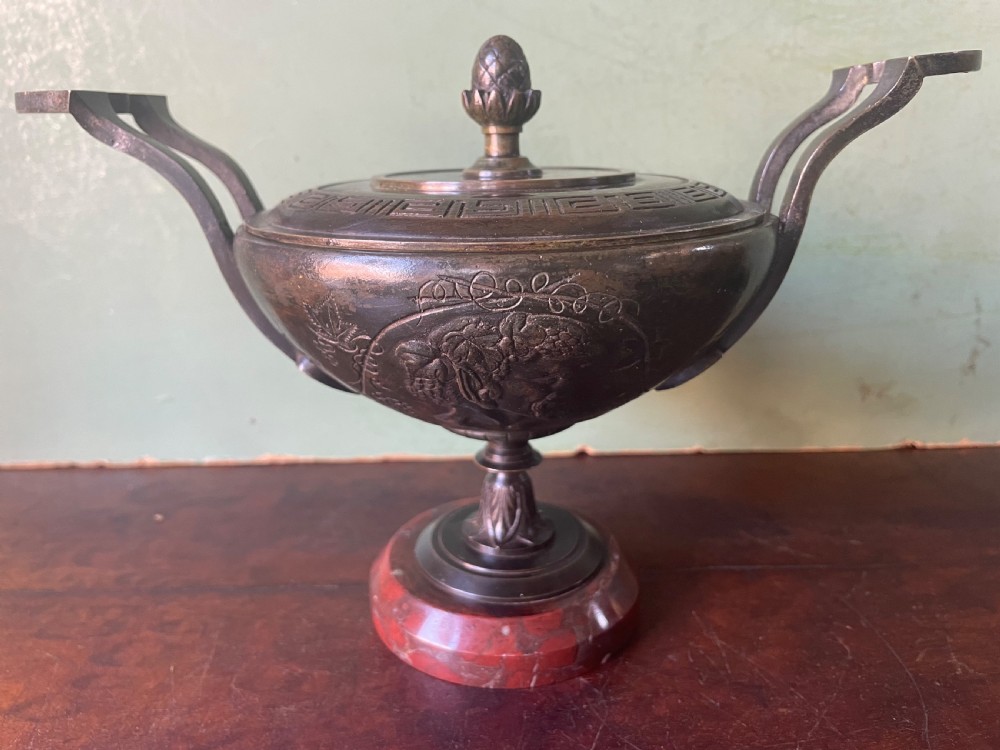 A nineteenth-century bronze lidded tazza featuring Greek key chasing and elevated handles, supported by a round red marble base. View VII