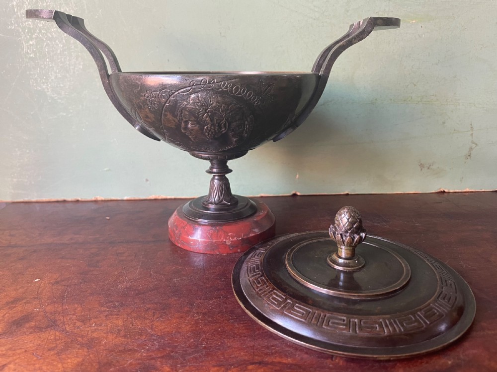 A nineteenth-century bronze lidded tazza featuring Greek key chasing and elevated handles, supported by a round red marble base. View XII