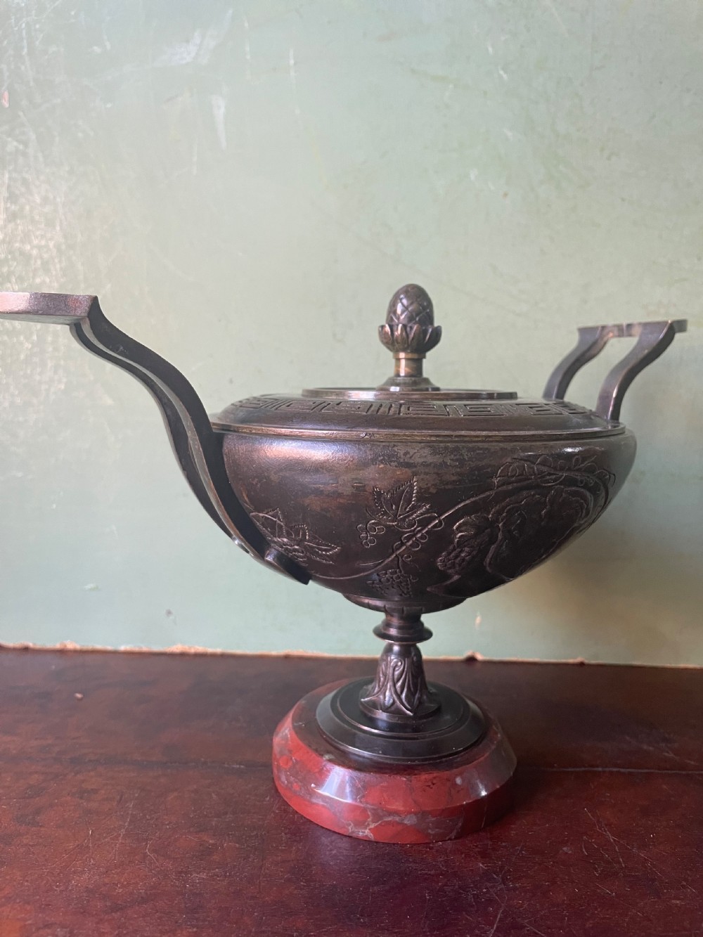 A nineteenth-century bronze lidded tazza featuring Greek key chasing and elevated handles, supported by a round red marble base. View XVI