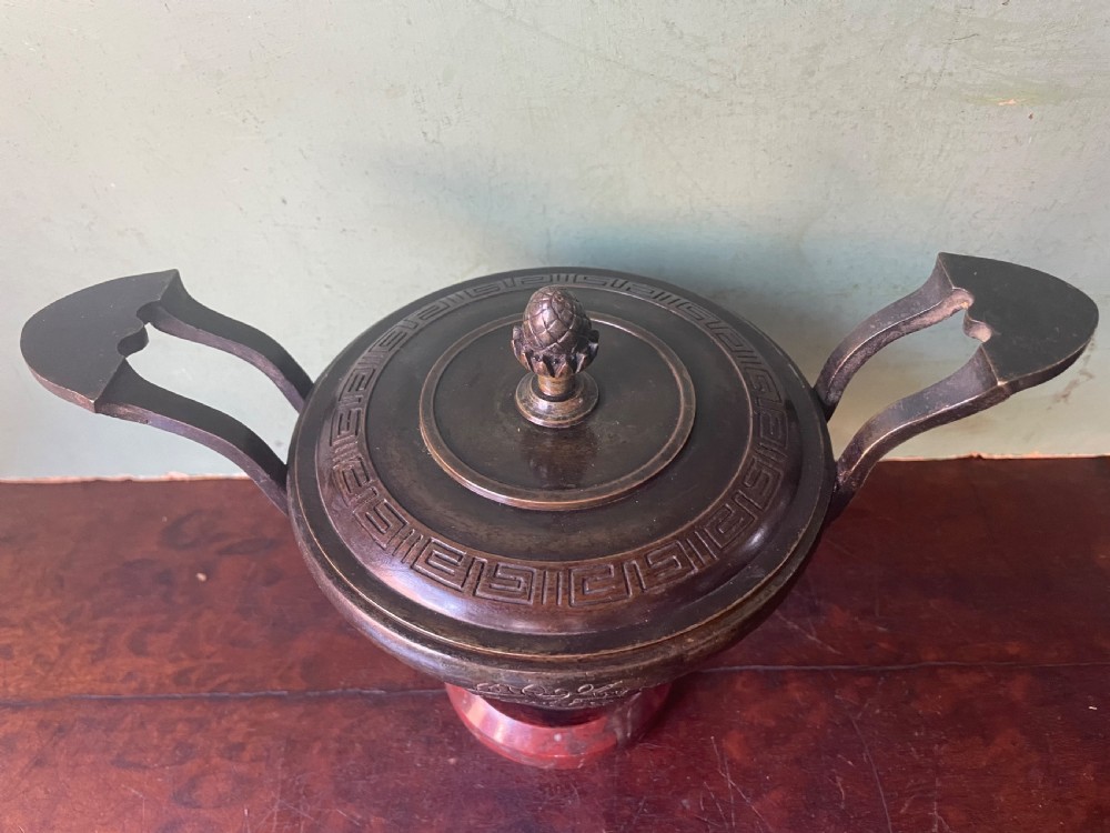 A nineteenth-century bronze lidded tazza featuring Greek key chasing and elevated handles, supported by a round red marble base. View XVII