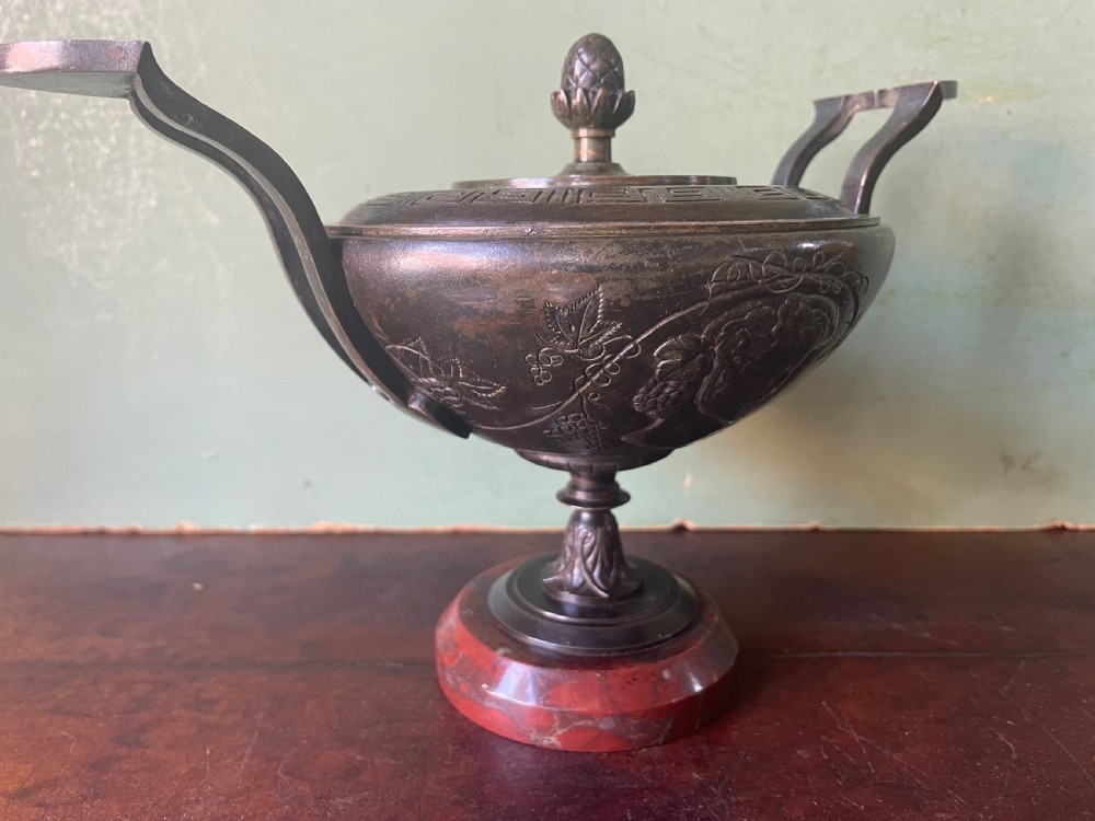 A nineteenth-century bronze lidded tazza featuring Greek key chasing and elevated handles, supported by a round red marble base. View XVIII