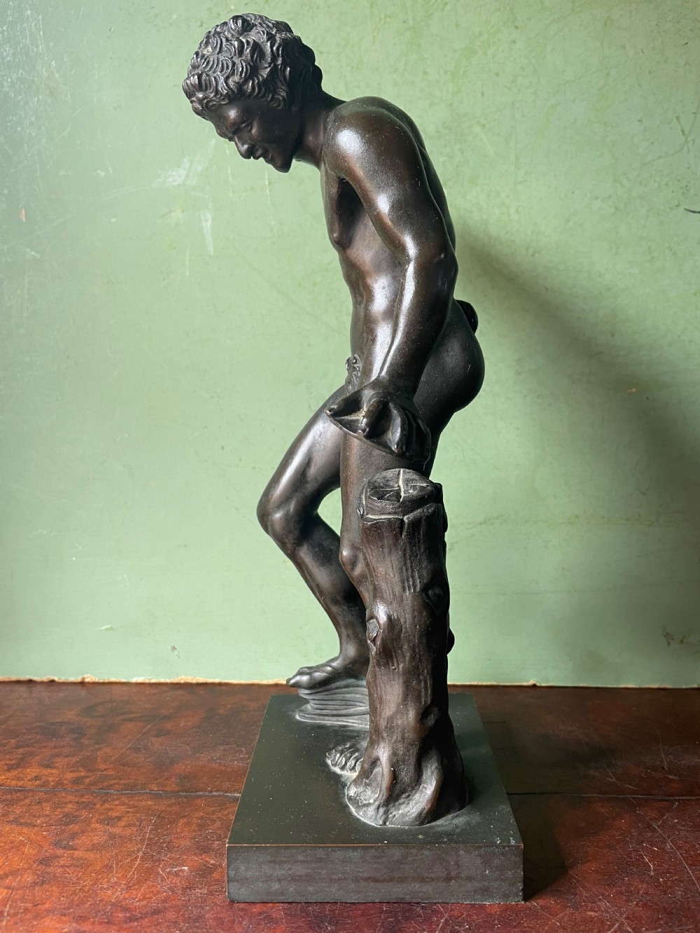 A dark patinated bronze sculpture depicting the classical figure of the Dancing Faun holding cymbals, mounted on a rectangular metal plinth. View V