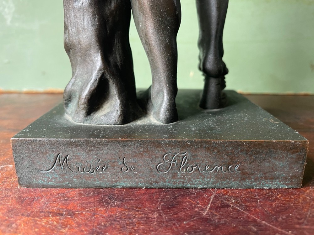 A dark patinated bronze sculpture depicting the classical figure of the Dancing Faun holding cymbals, mounted on a rectangular metal plinth. View IX