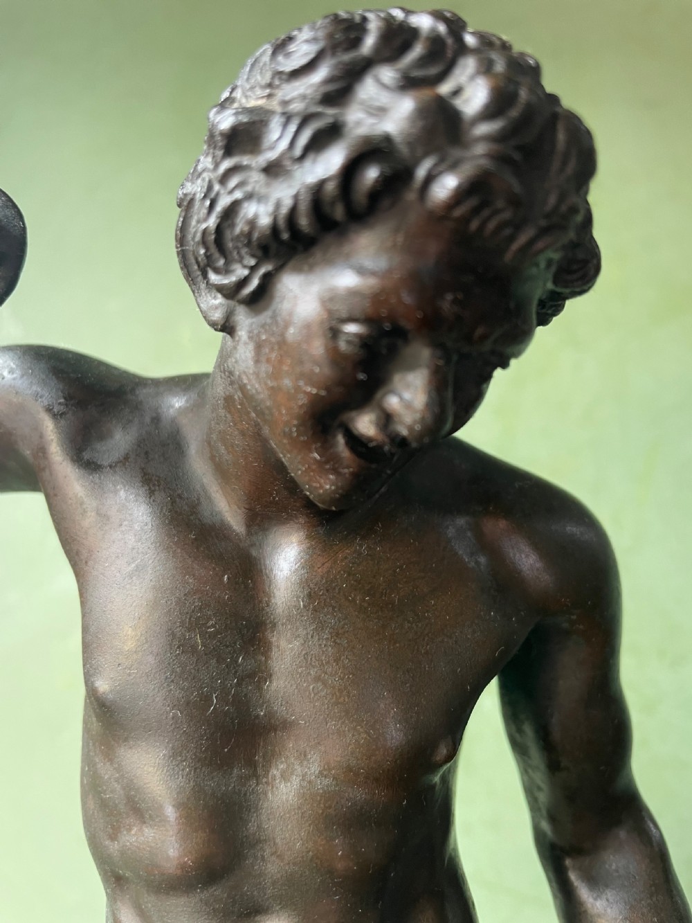A dark patinated bronze sculpture depicting the classical figure of the Dancing Faun holding cymbals, mounted on a rectangular metal plinth. View XIII