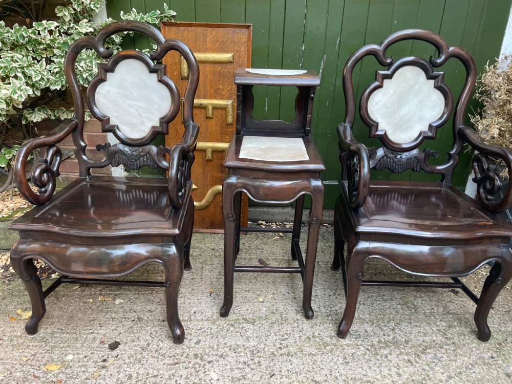 A pair of late Qing Dynasty dark hardwood armchairs with circular marble splat inlays flanking a matching two-tier stand. View III
