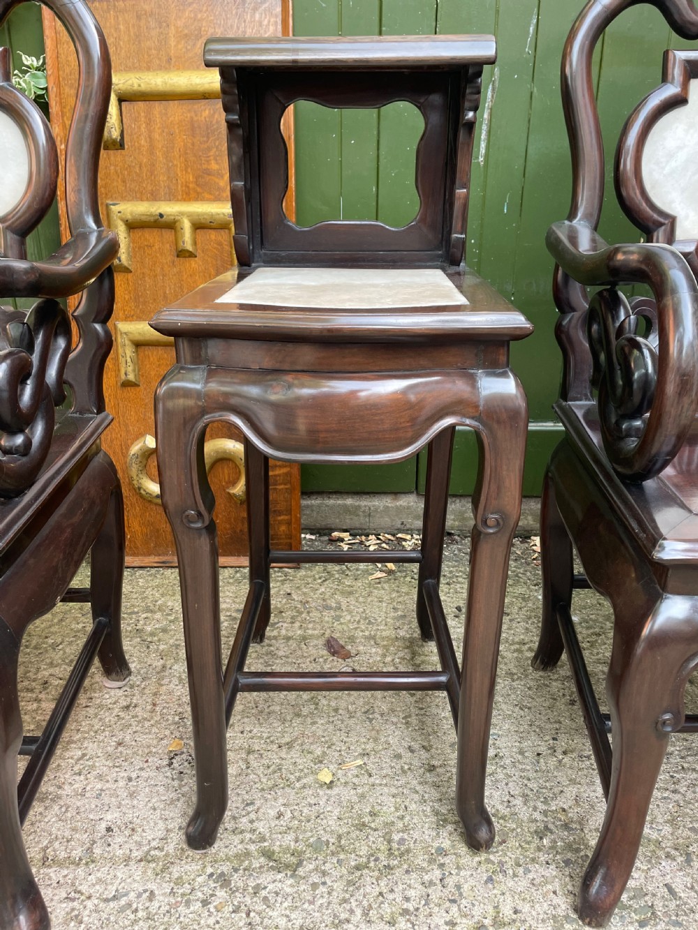 A pair of late Qing Dynasty dark hardwood armchairs with circular marble splat inlays flanking a matching two-tier stand. View VI