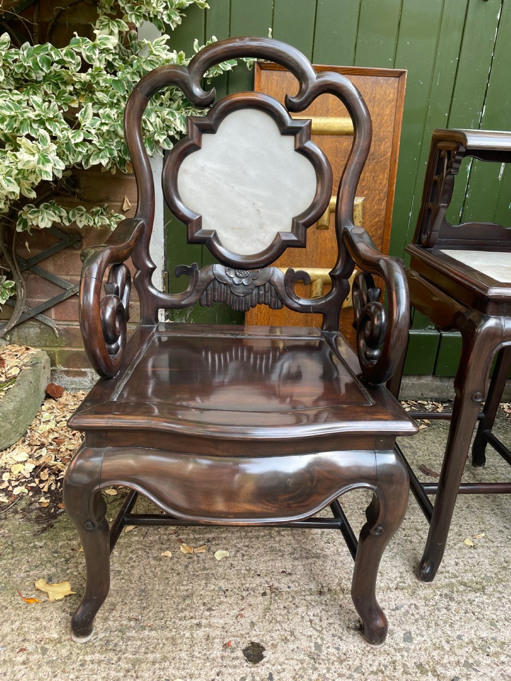 A pair of late Qing Dynasty dark hardwood armchairs with circular marble splat inlays flanking a matching two-tier stand. View VII