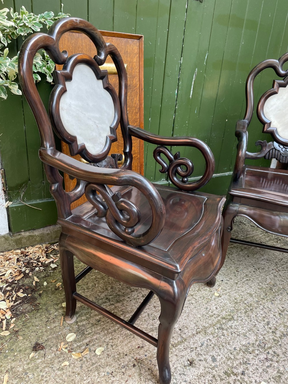 A pair of late Qing Dynasty dark hardwood armchairs with circular marble splat inlays flanking a matching two-tier stand. View X