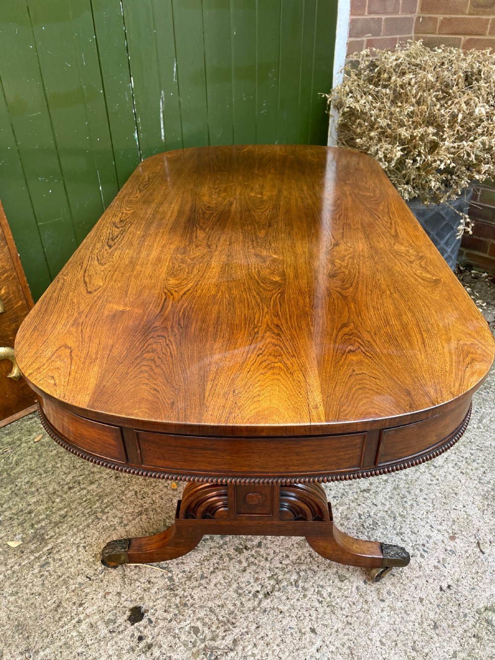 An early nineteenth-century George IV rosewood library table featuring two frieze drawers, a turned horizontal stretcher, and trestle legs on brass castors. View V