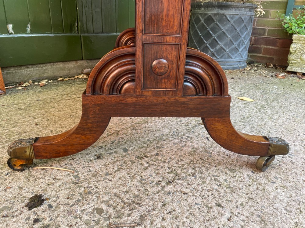 An early nineteenth-century George IV rosewood library table featuring two frieze drawers, a turned horizontal stretcher, and trestle legs on brass castors. View VI