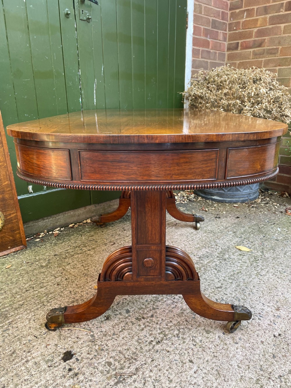An early nineteenth-century George IV rosewood library table featuring two frieze drawers, a turned horizontal stretcher, and trestle legs on brass castors. View VIII