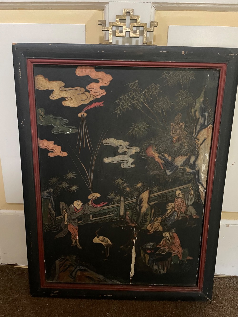 A set of four rectangular black lacquer panels framed in dark wood with red inner borders, depicting carved Chinese figurative scenes in landscape settings. View II