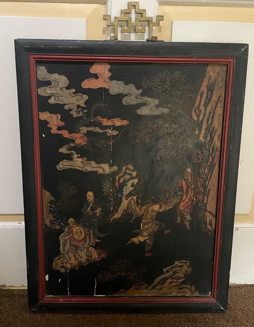 A set of four rectangular black lacquer panels framed in dark wood with red inner borders, depicting carved Chinese figurative scenes in landscape settings. View V