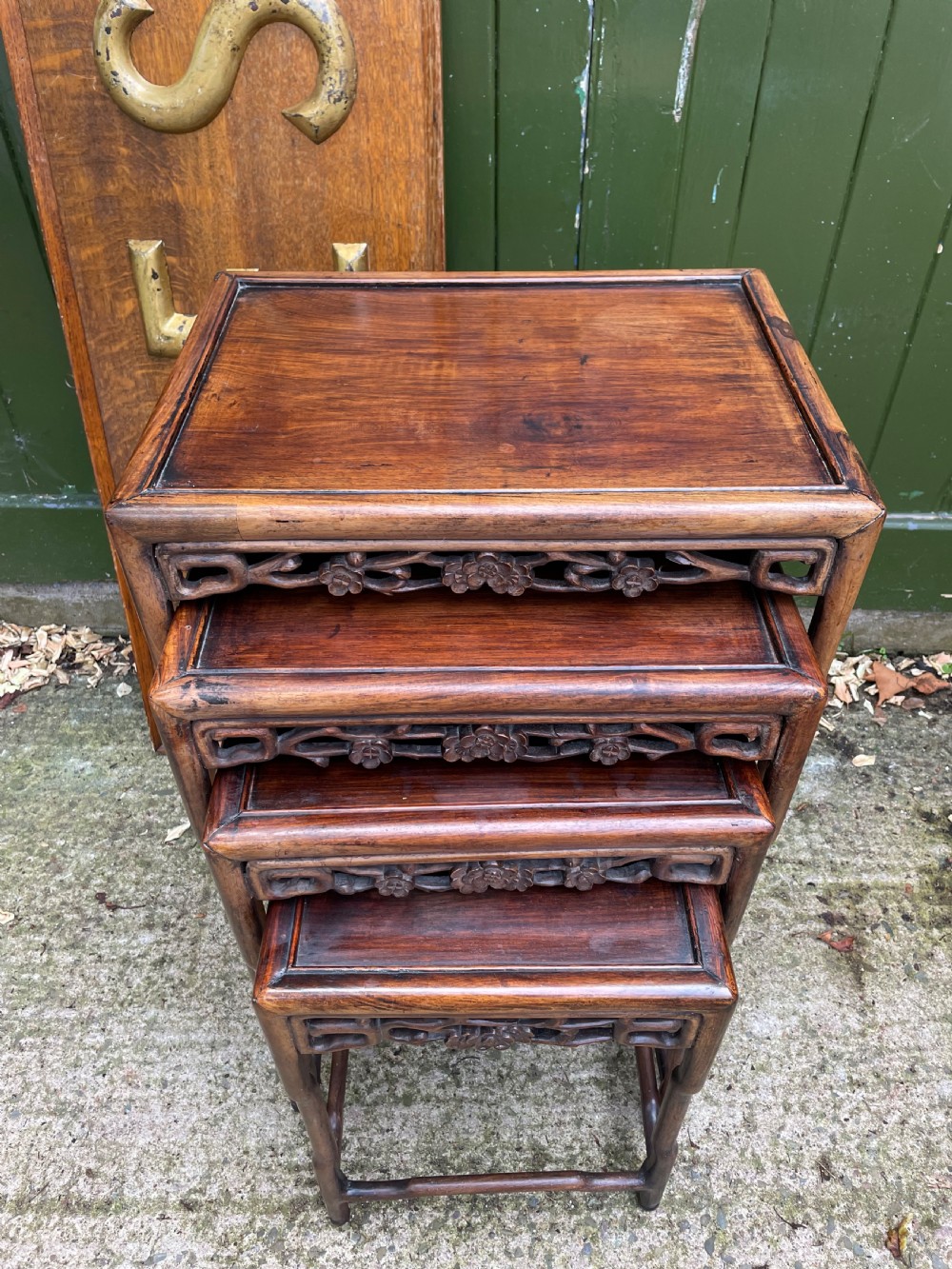 A set of four late nineteenth-century Chinese carved hardwood nesting tables stacked in size order with carved floral aprons.