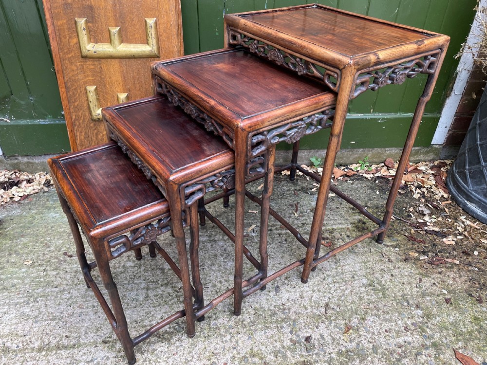 A set of four late nineteenth-century Chinese carved hardwood nesting tables stacked in size order with carved floral aprons. View II