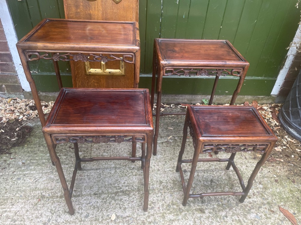 A set of four late nineteenth-century Chinese carved hardwood nesting tables stacked in size order with carved floral aprons. View X