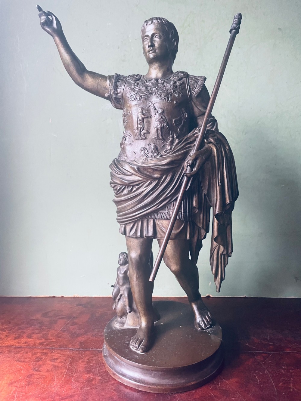 A late nineteenth-century dark bronze sculpture depicting Emperor Augustus of Prima Porta standing in classical armor with his right arm raised.