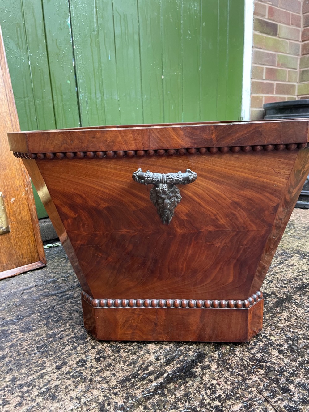 A George IV open mahogany wine cooler of classical sarcophagus form featuring flame mahogany veneer panels and carved bead moulding. View VII