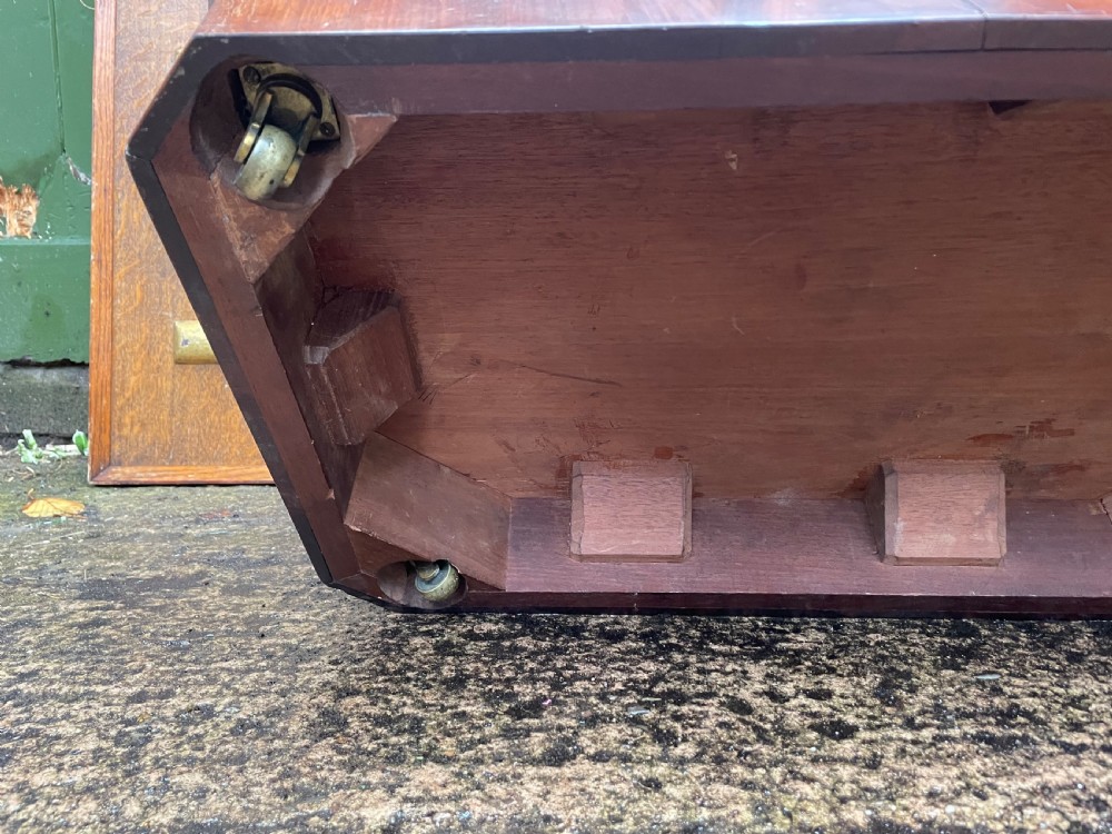A George IV open mahogany wine cooler of classical sarcophagus form featuring flame mahogany veneer panels and carved bead moulding. View XII