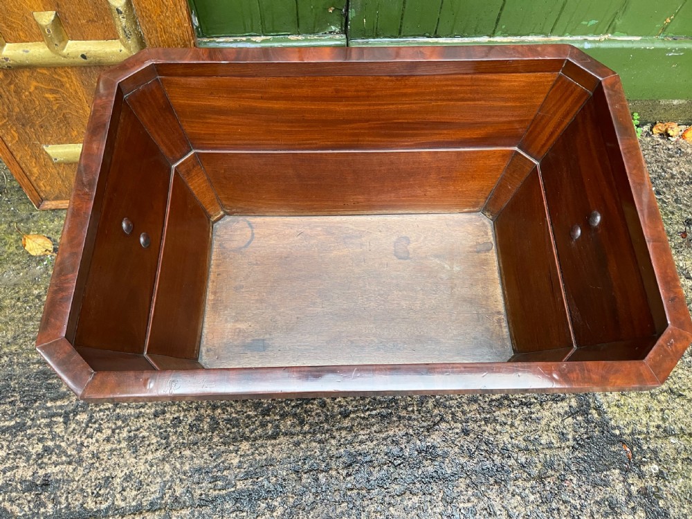 A George IV open mahogany wine cooler of classical sarcophagus form featuring flame mahogany veneer panels and carved bead moulding. View XIII