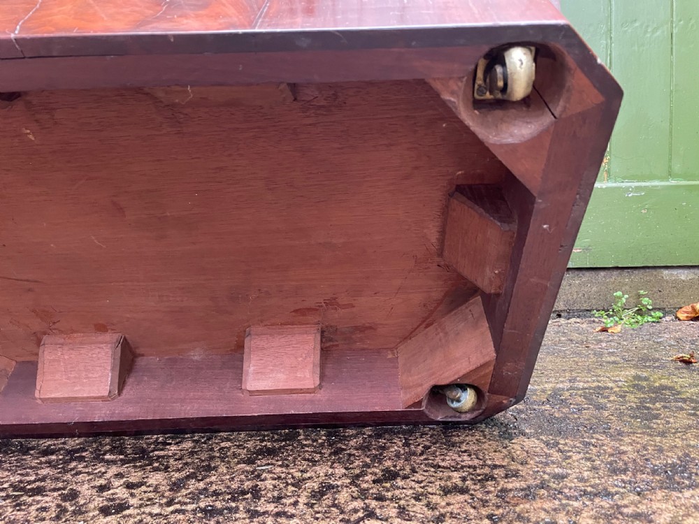 A George IV open mahogany wine cooler of classical sarcophagus form featuring flame mahogany veneer panels and carved bead moulding. View XIV