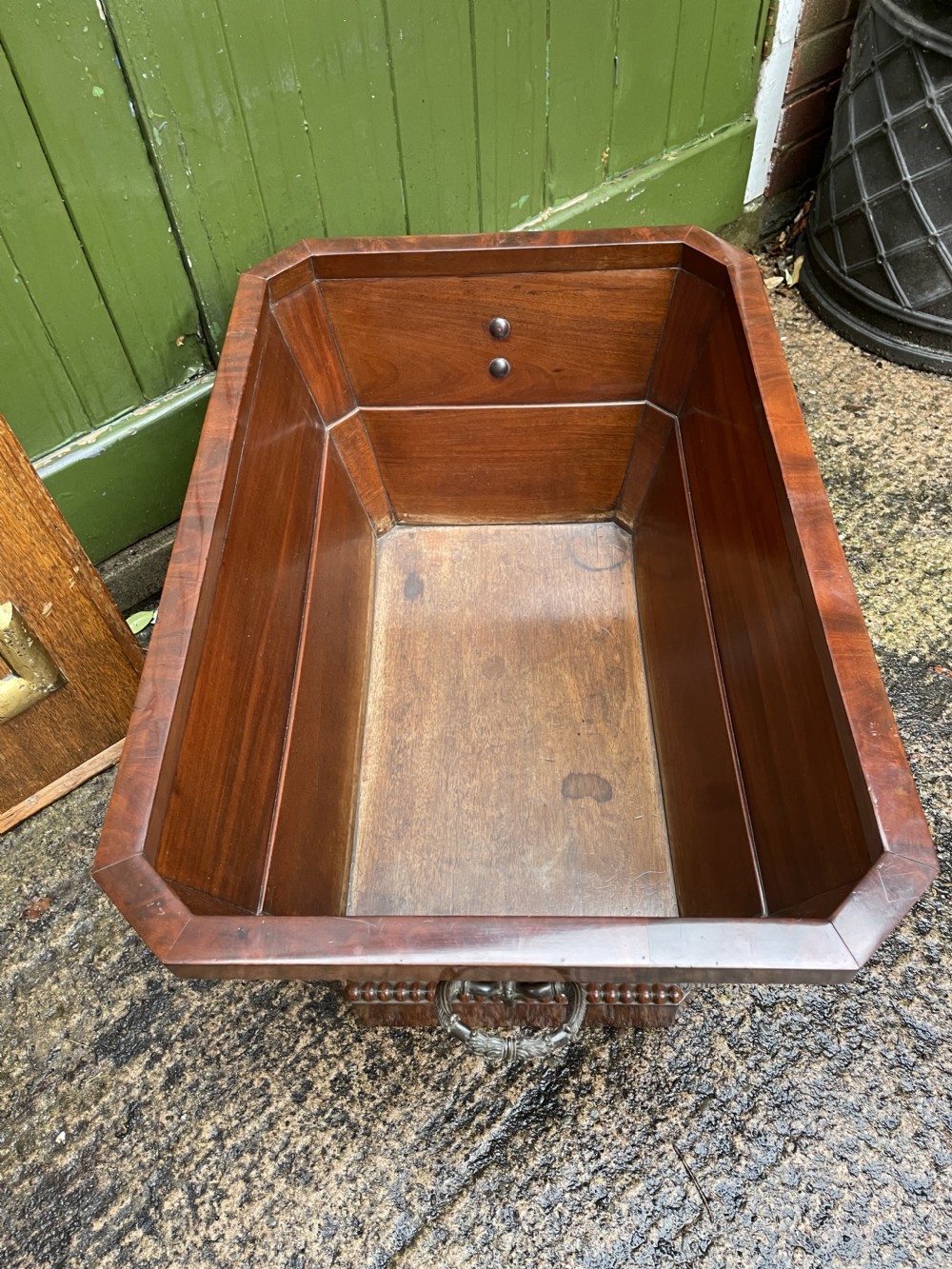 A George IV open mahogany wine cooler of classical sarcophagus form featuring flame mahogany veneer panels and carved bead moulding. View XVII