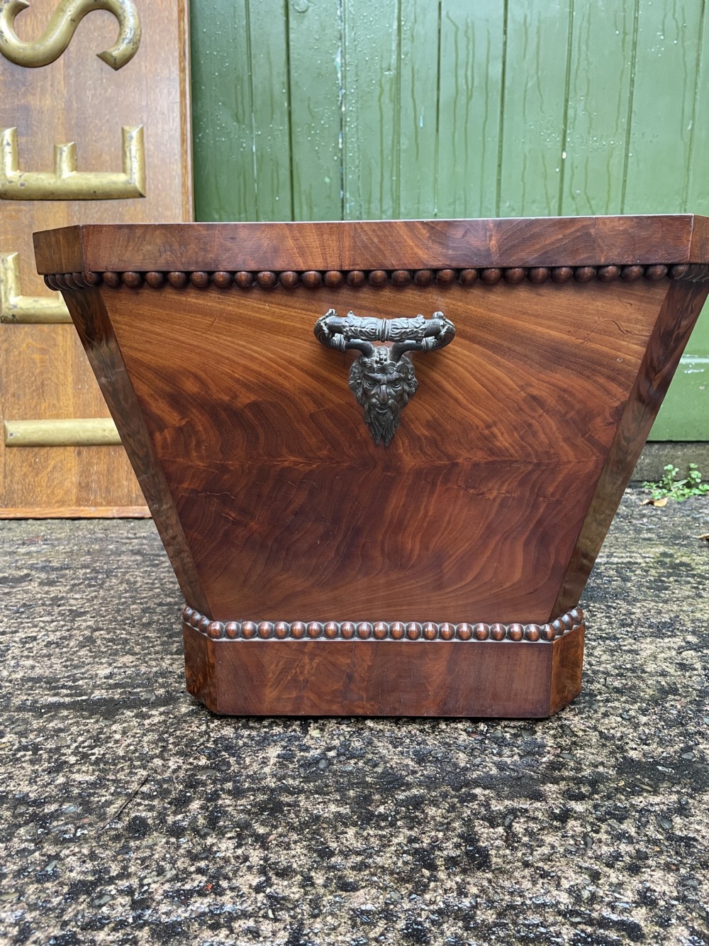 A George IV open mahogany wine cooler of classical sarcophagus form featuring flame mahogany veneer panels and carved bead moulding. View XVIII