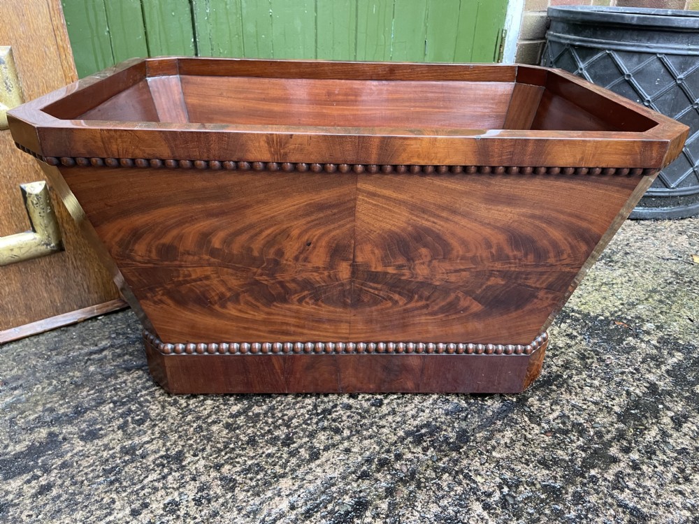 A George IV open mahogany wine cooler of classical sarcophagus form featuring flame mahogany veneer panels and carved bead moulding. View XXIII