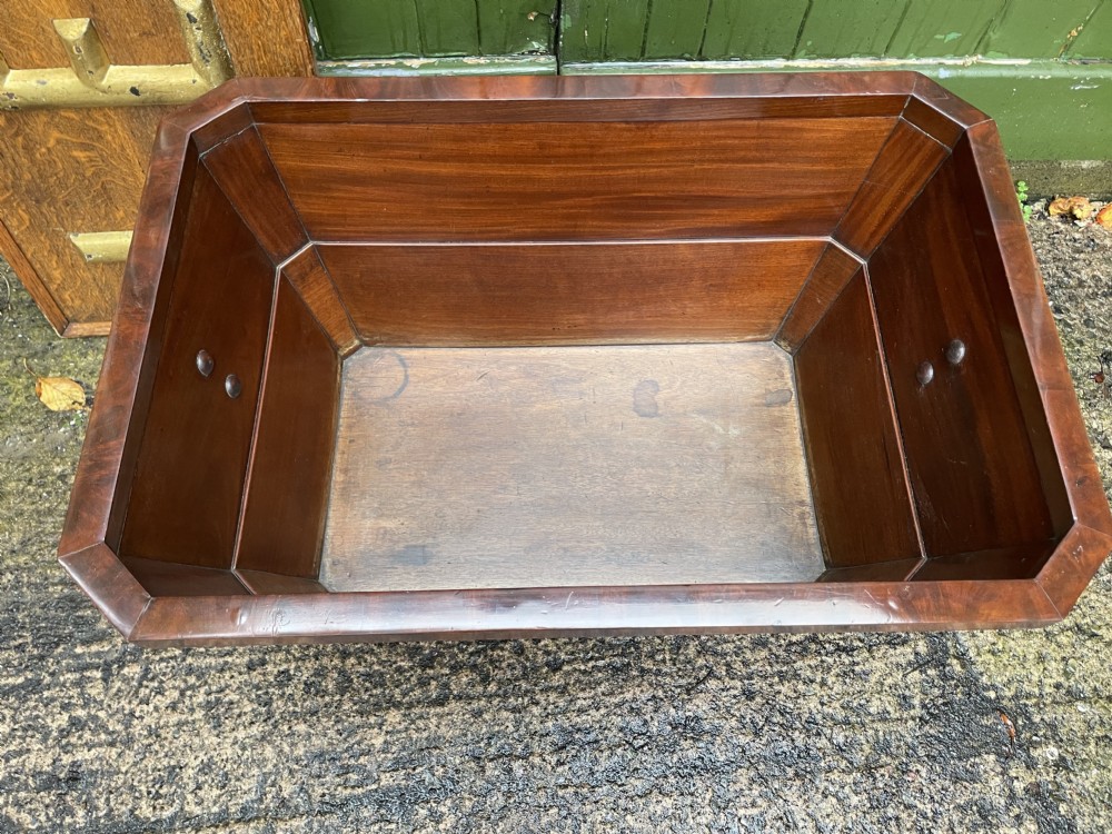 A George IV open mahogany wine cooler of classical sarcophagus form featuring flame mahogany veneer panels and carved bead moulding. View XXIV