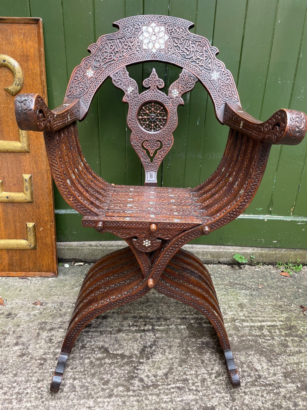 A Syrian dark walnut X-frame armchair featuring intricate Arabic calligraphy carvings and geometric mother-of-pearl shell inlay throughout. View IV