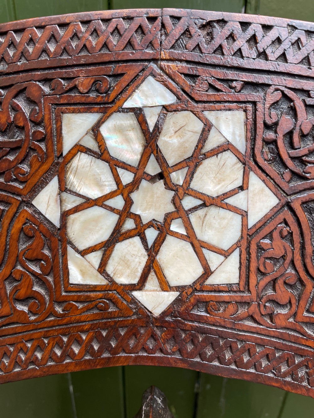A Syrian dark walnut X-frame armchair featuring intricate Arabic calligraphy carvings and geometric mother-of-pearl shell inlay throughout. View VI